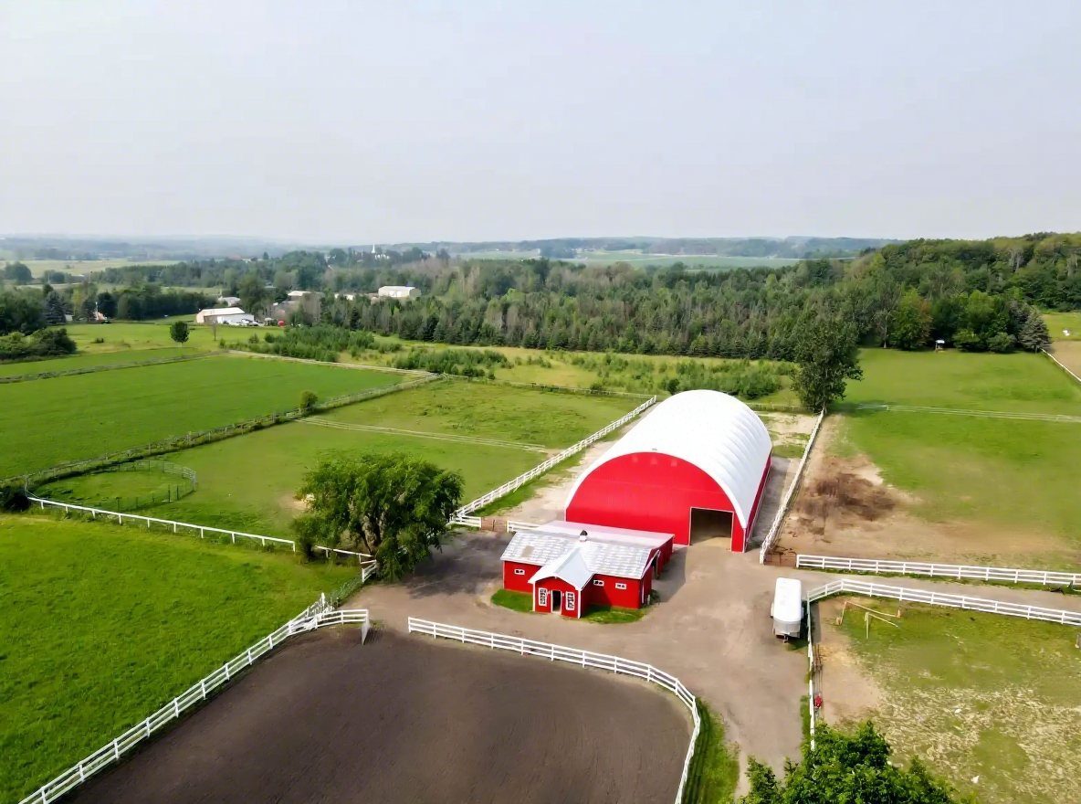 Red barn with white arch fabric roof in green fields